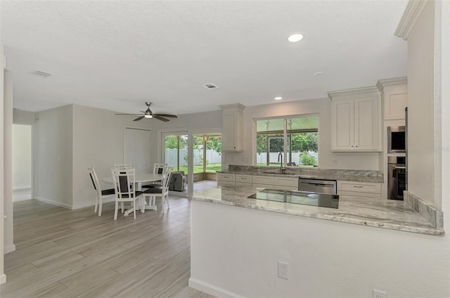 kitchen with visible vents, appliances with stainless steel finishes, light wood-style floors, a sink, and light stone countertops