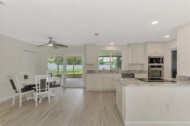 kitchen with visible vents, light wood-style floors, white cabinets, light stone countertops, and black appliances