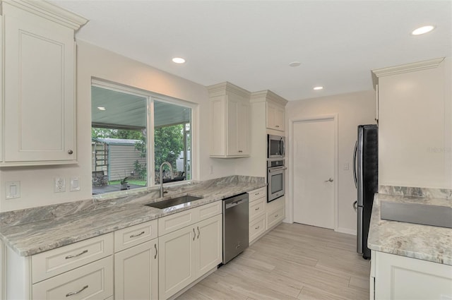 kitchen featuring stainless steel appliances, recessed lighting, light wood-style floors, a sink, and light stone countertops