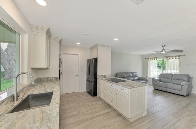 kitchen featuring open floor plan, black appliances, light stone counters, and a sink