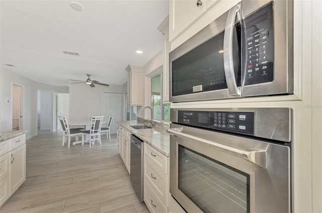 kitchen featuring visible vents, light wood-style flooring, light stone countertops, stainless steel appliances, and a sink