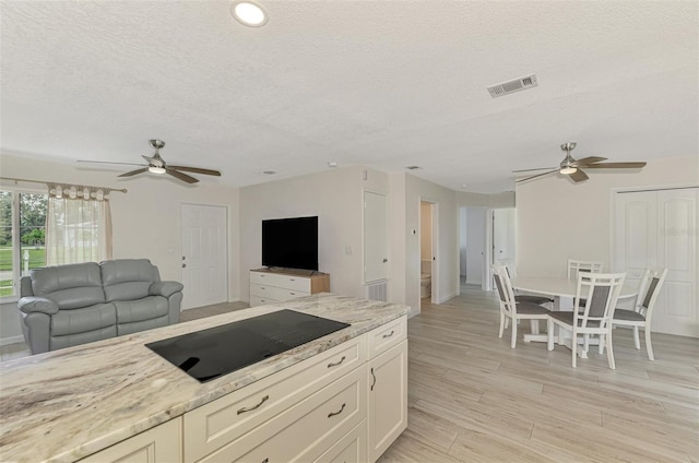 kitchen featuring open floor plan, light stone counters, and black electric cooktop