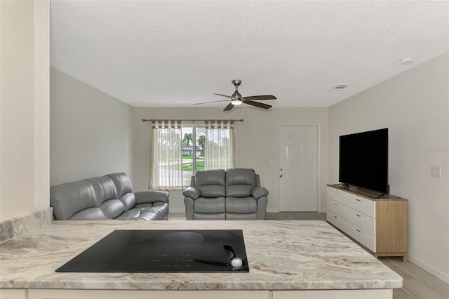 living room with light wood finished floors, visible vents, ceiling fan, a textured ceiling, and baseboards