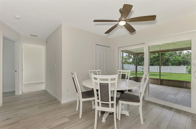 dining area featuring light wood-style floors, baseboards, visible vents, and a sunroom