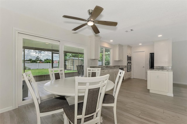 dining room featuring baseboards, visible vents, light wood-style flooring, a textured ceiling, and recessed lighting