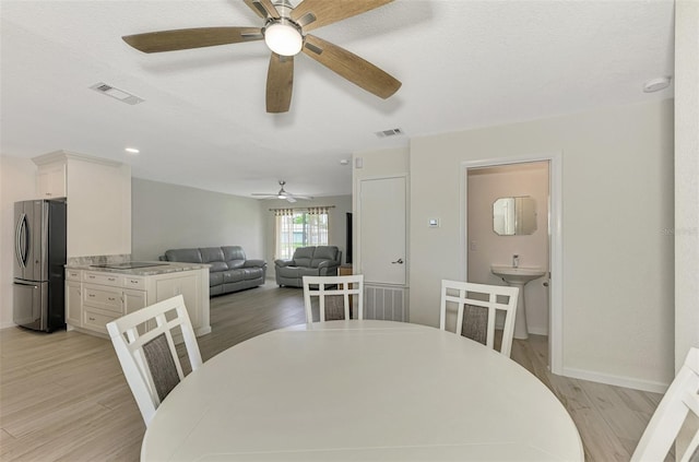 dining area featuring light wood finished floors, baseboards, visible vents, and a textured ceiling