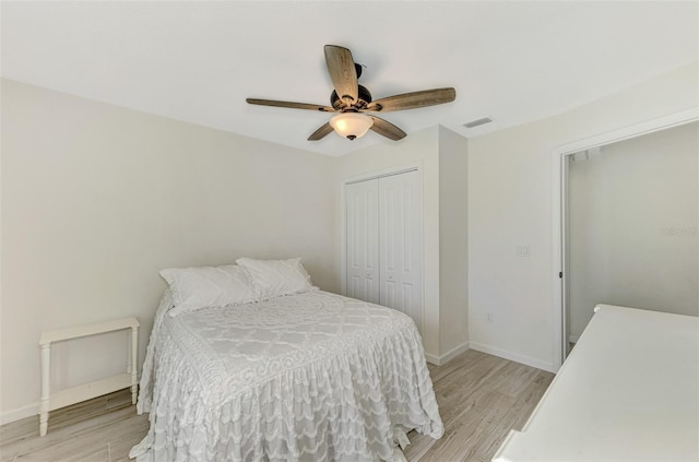 bedroom featuring a ceiling fan, a closet, light wood-style flooring, and baseboards