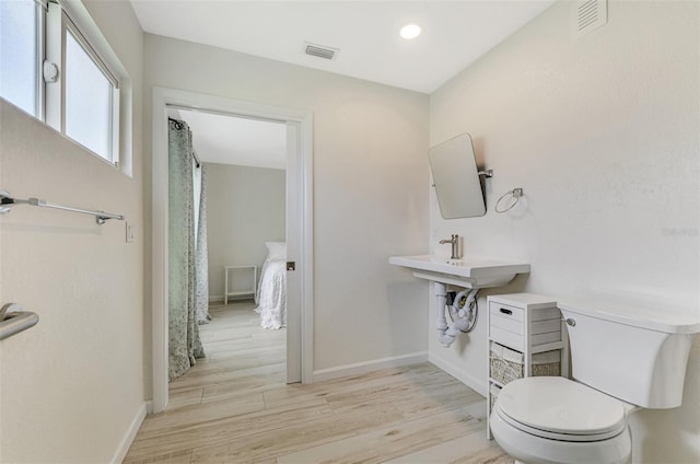 bathroom with baseboards, visible vents, toilet, and wood finished floors