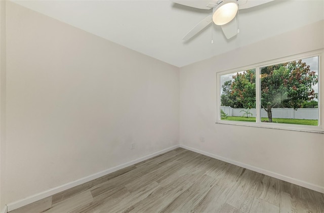 unfurnished room with ceiling fan, light wood finished floors, and baseboards