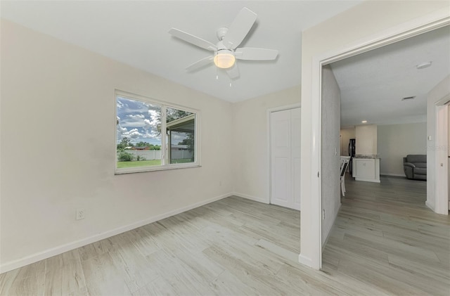 spare room with light wood-type flooring, ceiling fan, and baseboards