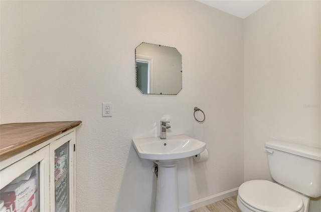 bathroom featuring toilet, baseboards, and wood finished floors