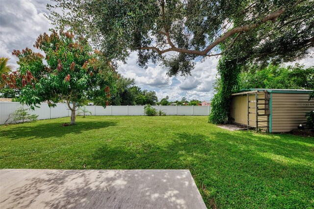 view of yard featuring an outbuilding, a fenced backyard, and a shed