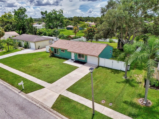 view of front of house featuring an attached garage, driveway, a front lawn, and fence