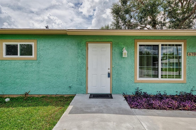 doorway to property featuring stucco siding