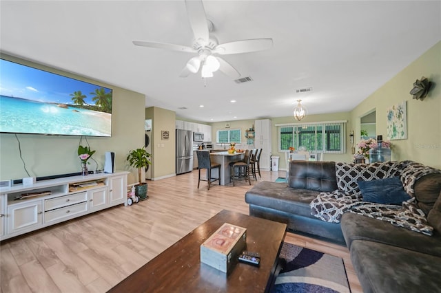 living room with light hardwood / wood-style flooring and ceiling fan with notable chandelier