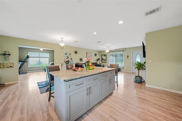 kitchen featuring a kitchen bar, a wealth of natural light, visible vents, and gray cabinetry