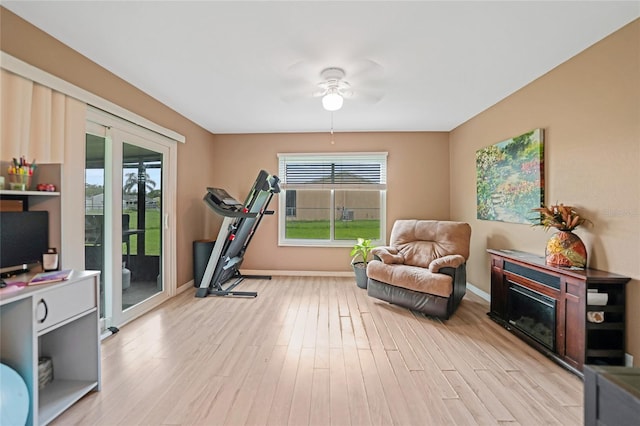 exercise room featuring light wood-style floors, baseboards, and a ceiling fan