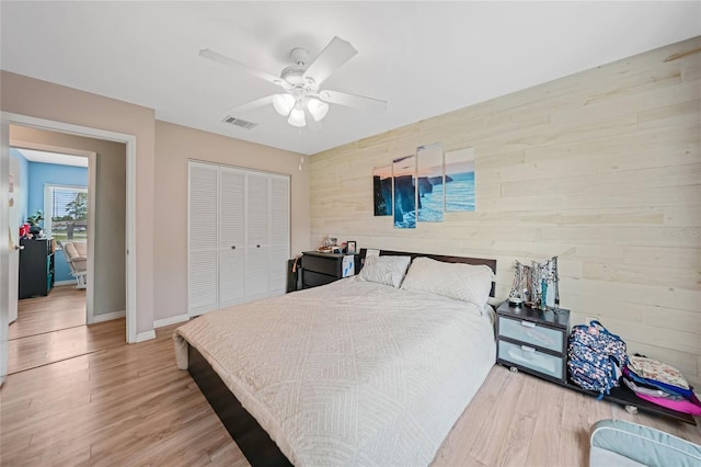 bedroom with wood walls, a closet, wood finished floors, and baseboards