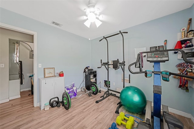 workout room featuring a ceiling fan, visible vents, baseboards, and wood finished floors