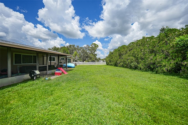 view of yard with a sunroom and fence