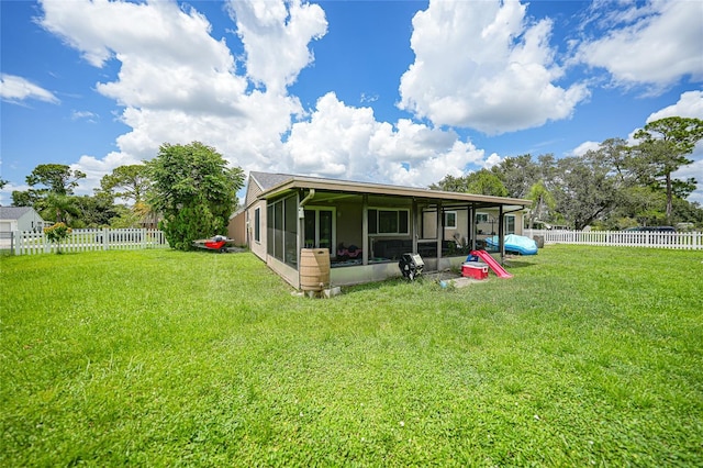 back of property featuring a lawn, a fenced backyard, and a sunroom