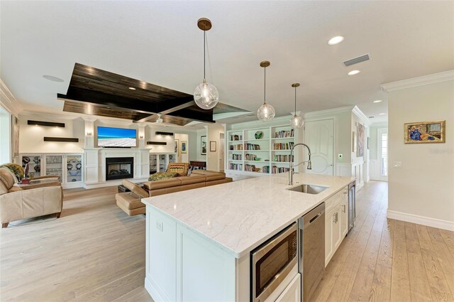 kitchen with white cabinets, an island with sink, appliances with stainless steel finishes, decorative light fixtures, and a sink