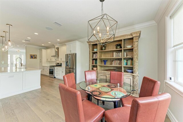 dining area with a wealth of natural light, a notable chandelier, crown molding, and light wood finished floors