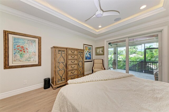 bedroom with baseboards, access to exterior, a tray ceiling, crown molding, and light wood-type flooring