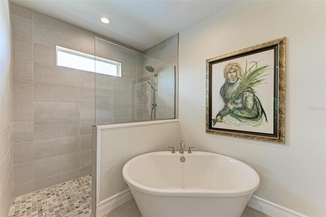 bathroom featuring a freestanding tub, baseboards, and a walk in shower