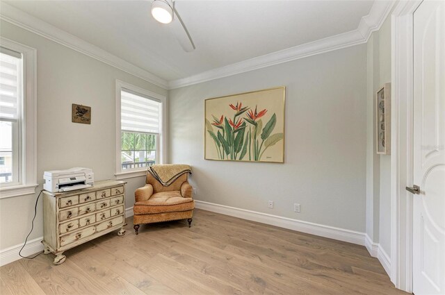 living area with crown molding, light wood-style flooring, and baseboards