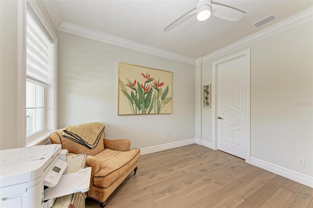 living area featuring light wood finished floors, baseboards, visible vents, and ornamental molding