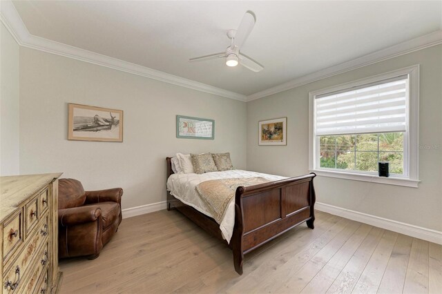 bedroom featuring a ceiling fan, baseboards, crown molding, and light wood finished floors