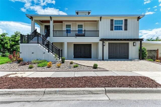 view of front of home with a garage, covered porch, stairs, decorative driveway, and board and batten siding