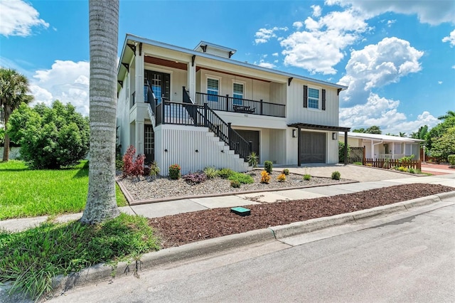 view of front of house featuring an attached garage, covered porch, stairs, and decorative driveway