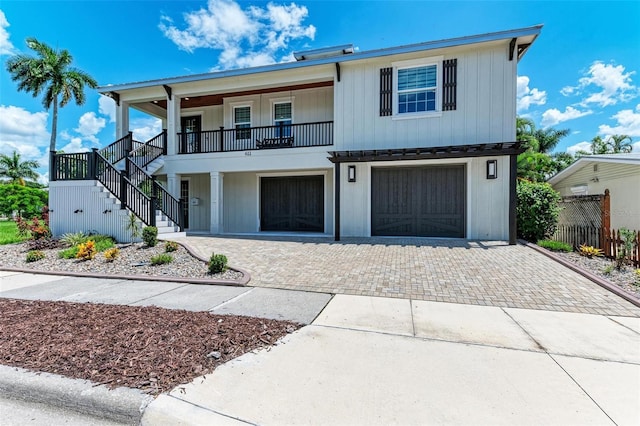 view of front of property with a garage, decorative driveway, a porch, and stairs