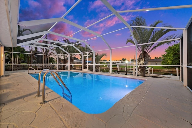 pool at dusk with a patio, glass enclosure, and an outdoor pool