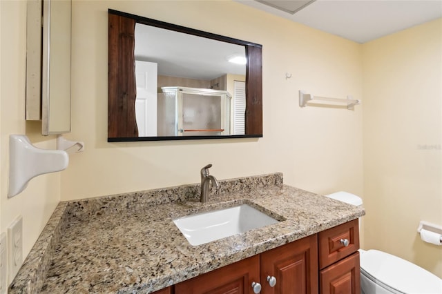 bathroom with toilet, a shower with door, and vanity