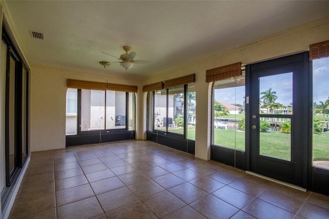 unfurnished sunroom featuring ceiling fan and a wealth of natural light