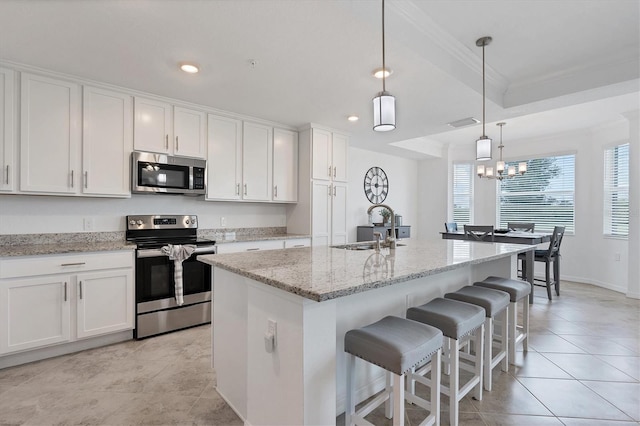 kitchen featuring a chandelier, light stone countertops, appliances with stainless steel finishes, and white cabinetry