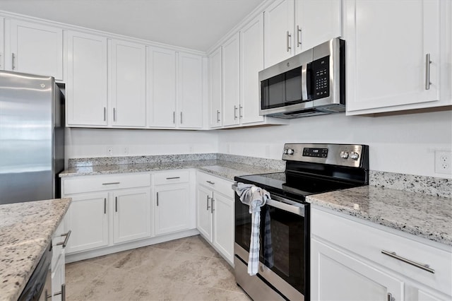 kitchen with light stone counters, light tile patterned floors, appliances with stainless steel finishes, and white cabinets