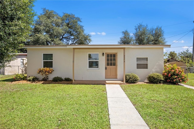 ranch-style home with fence, a front lawn, and stucco siding