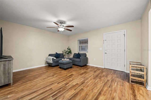 sitting room with hardwood / wood-style flooring, heating unit, and ceiling fan