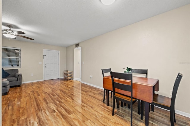 dining space featuring light wood-type flooring, ceiling fan, and a textured ceiling