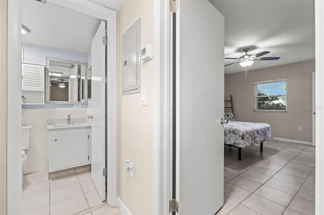 corridor with electric panel, tile walls, sink, and light tile patterned floors