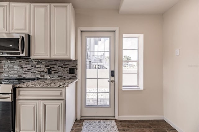 kitchen featuring a healthy amount of sunlight, stainless steel appliances, light stone counters, and backsplash