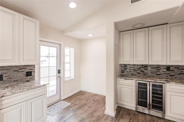 kitchen featuring light stone counters, wine cooler, hardwood / wood-style floors, and backsplash