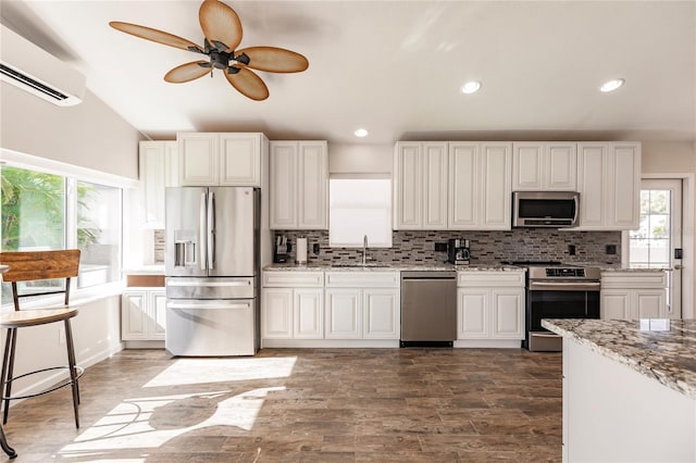 kitchen with plenty of natural light, backsplash, stainless steel appliances, and a wall mounted air conditioner