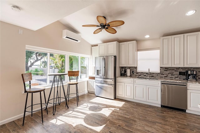 kitchen featuring dark hardwood / wood-style flooring, ceiling fan, decorative backsplash, appliances with stainless steel finishes, and an AC wall unit