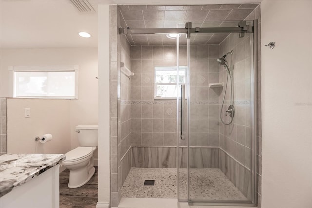 bathroom featuring vanity, toilet, hardwood / wood-style flooring, and an enclosed shower