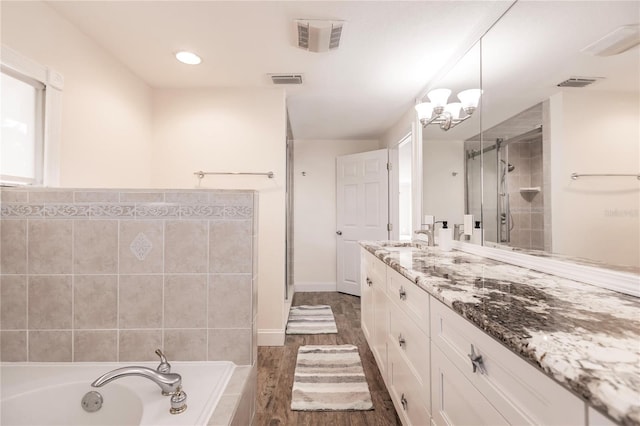 bathroom with plus walk in shower, wood-type flooring, a notable chandelier, and vanity